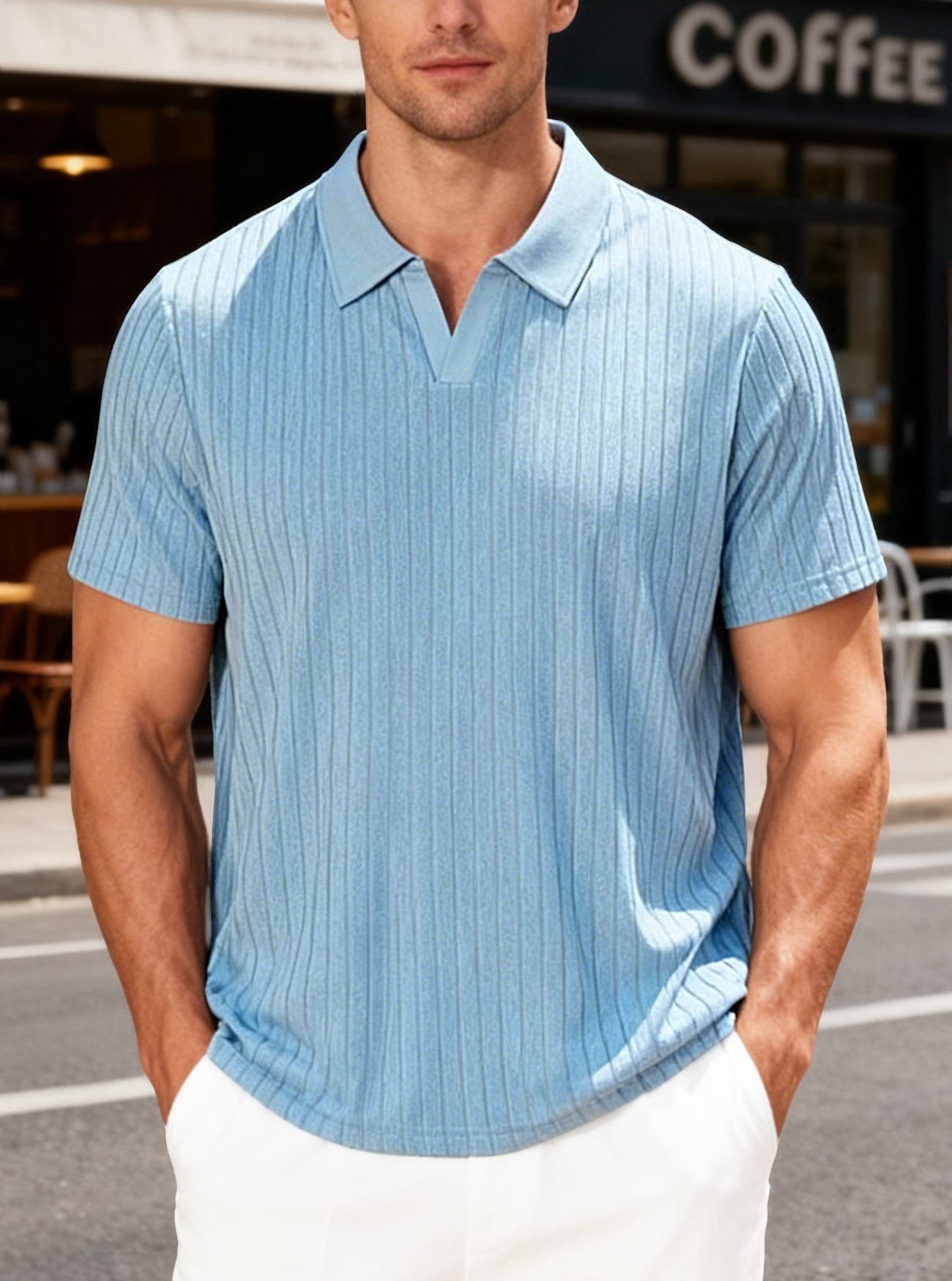 Man wearing a light blue striped polo shirt and white pants standing on a street.