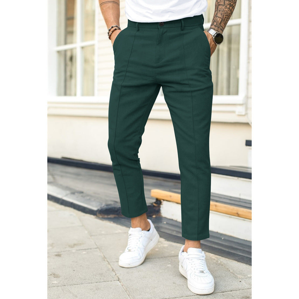 Person wearing green pants and white sneakers standing on a sidewalk.