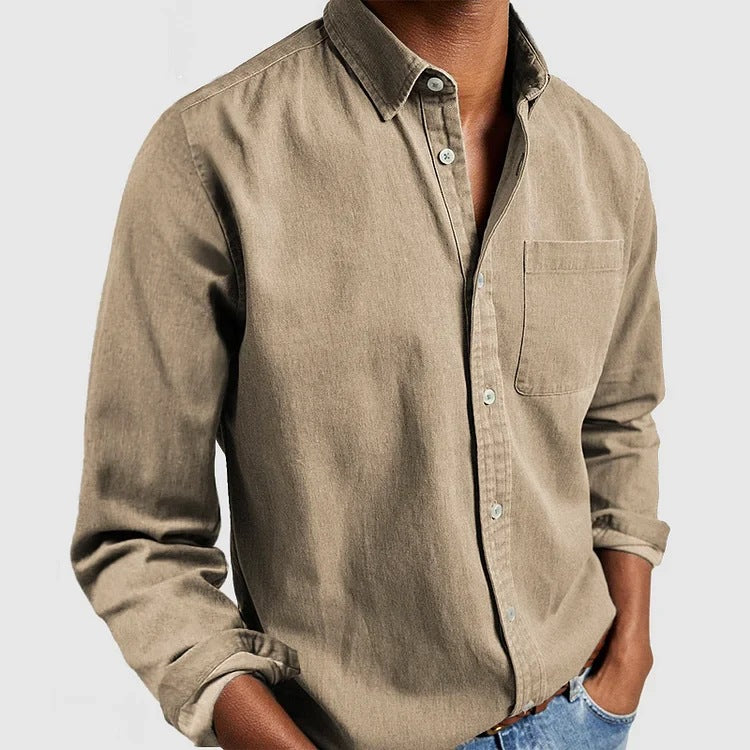 Man wearing a beige button-up shirt and blue jeans on a light gray background