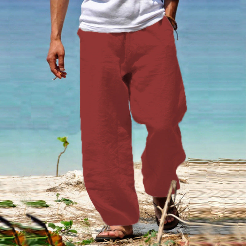 Person wearing red pants standing on a beach with blue water in the background
