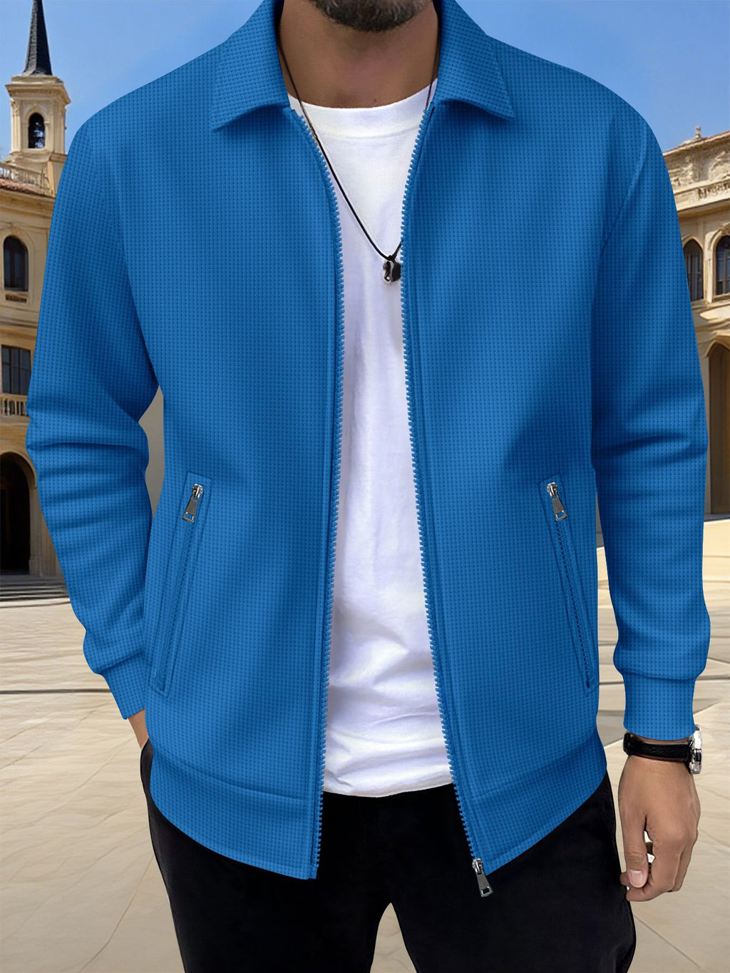 Person wearing a blue jacket over a white shirt with a blurred architectural background