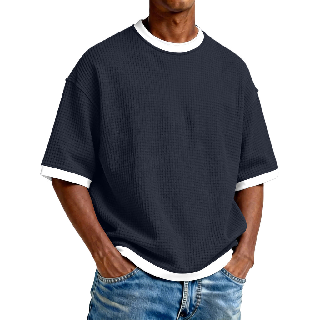 Man wearing a navy blue textured t-shirt with white trim on a white background