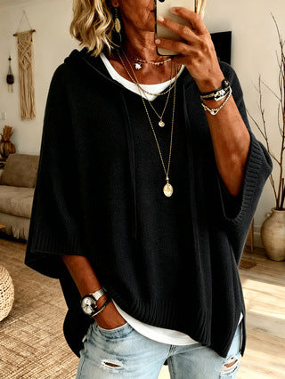 Person wearing a black sweater over a white shirt with distressed jeans, taking a mirror selfie.