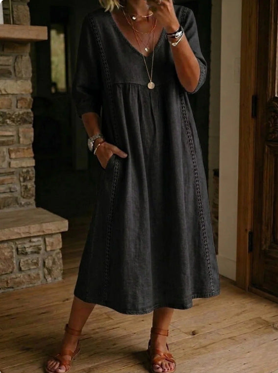 Woman wearing a dark gray dress indoors with a stone fireplace in the background
