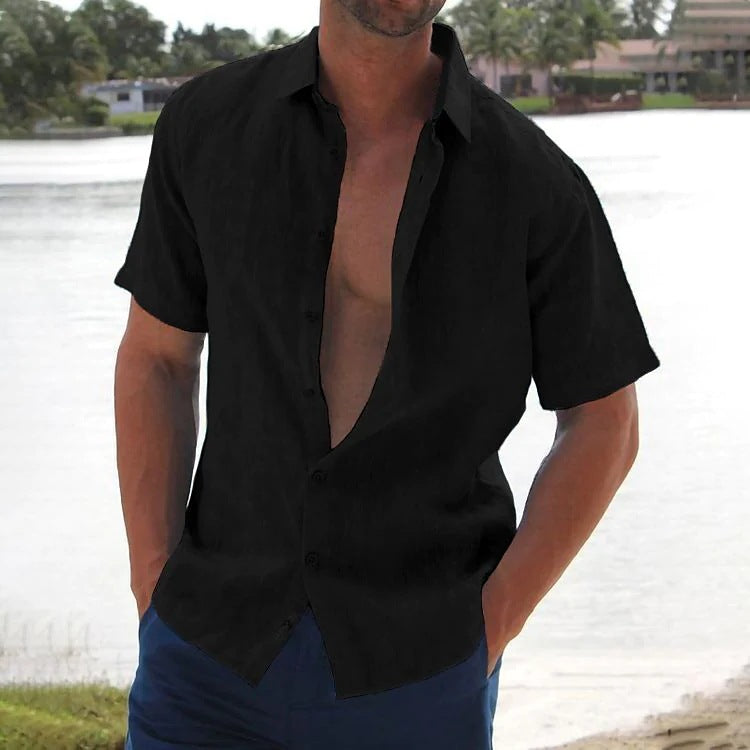 Man wearing a black open-neck shirt with a blurred background