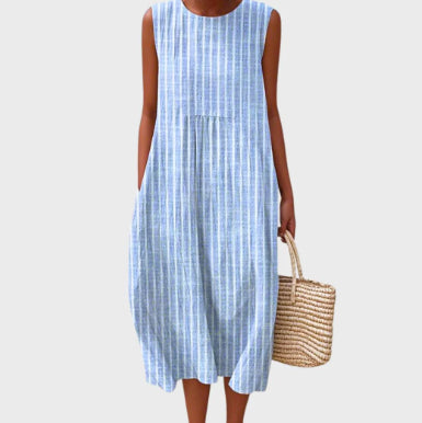 Woman wearing a blue and white checkered dress holding a straw bag on a white background