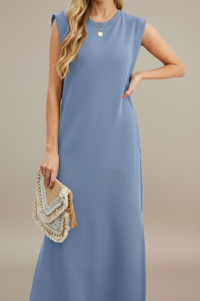 Woman wearing a blue sleeveless dress holding a beaded clutch on a white background