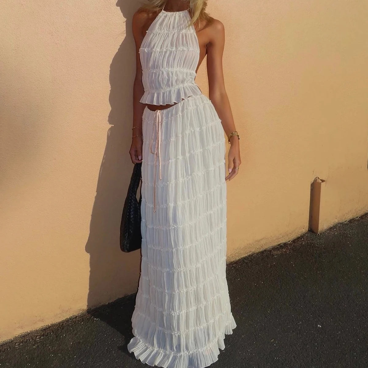 Woman wearing a white lace dress against a beige wall.