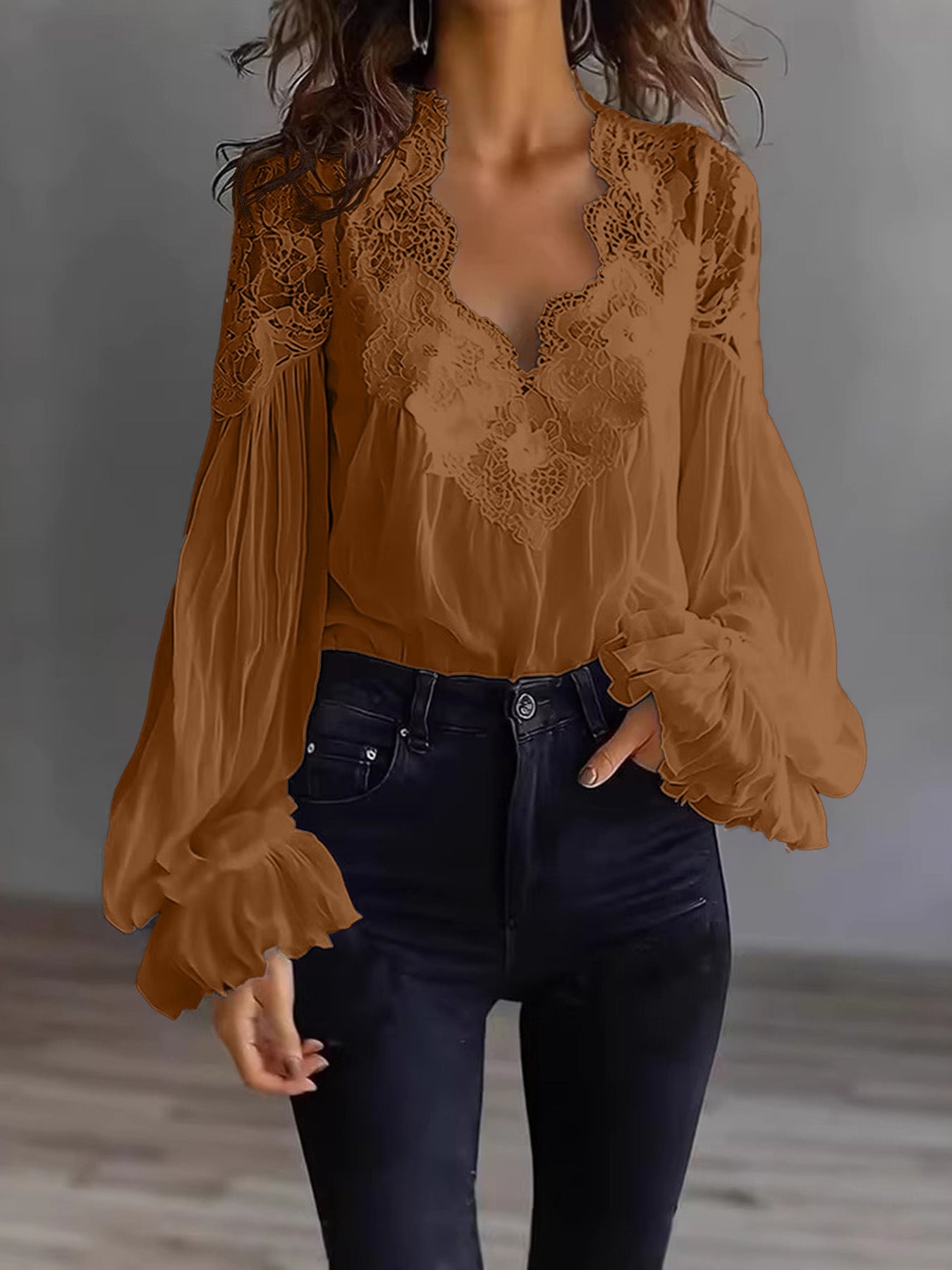 Person wearing a brown lace top and dark jeans against a neutral background