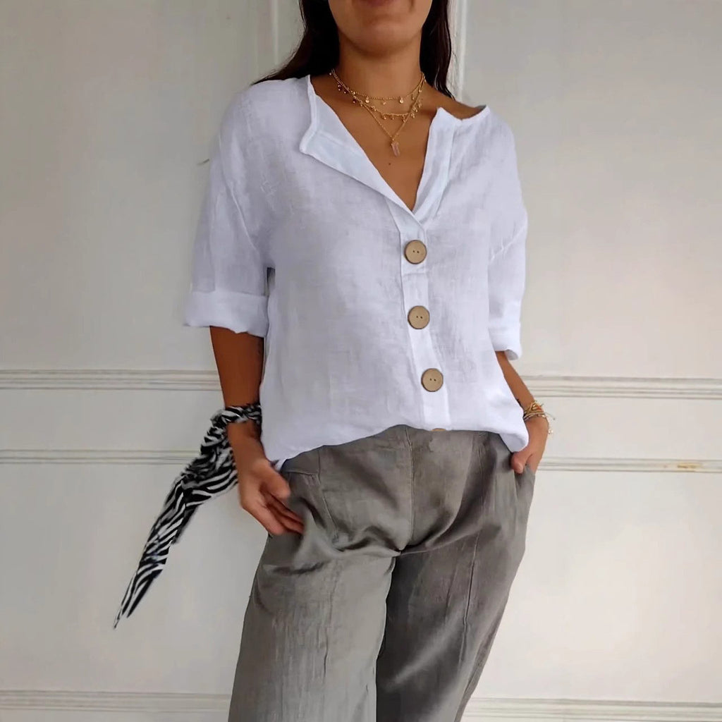 Person wearing a white button-up shirt and gray pants against a neutral background