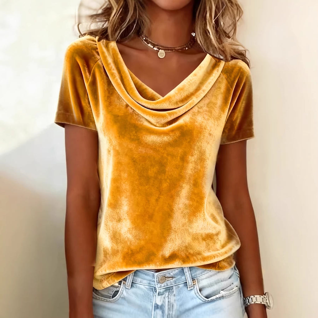 Person wearing a mustard yellow velvet top and light blue jeans against a neutral background