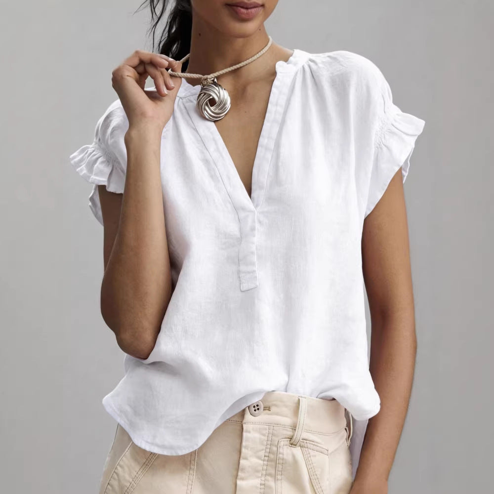 Woman wearing a white blouse with ruffled sleeves on a gray background