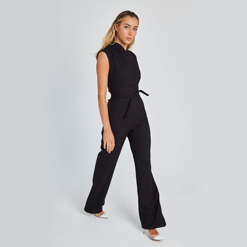Woman wearing a black jumpsuit on a light gray background