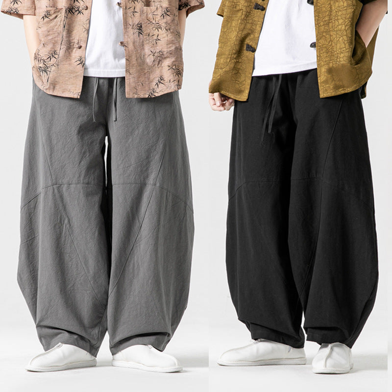Two people wearing wide-leg pants and white shoes on a plain background
