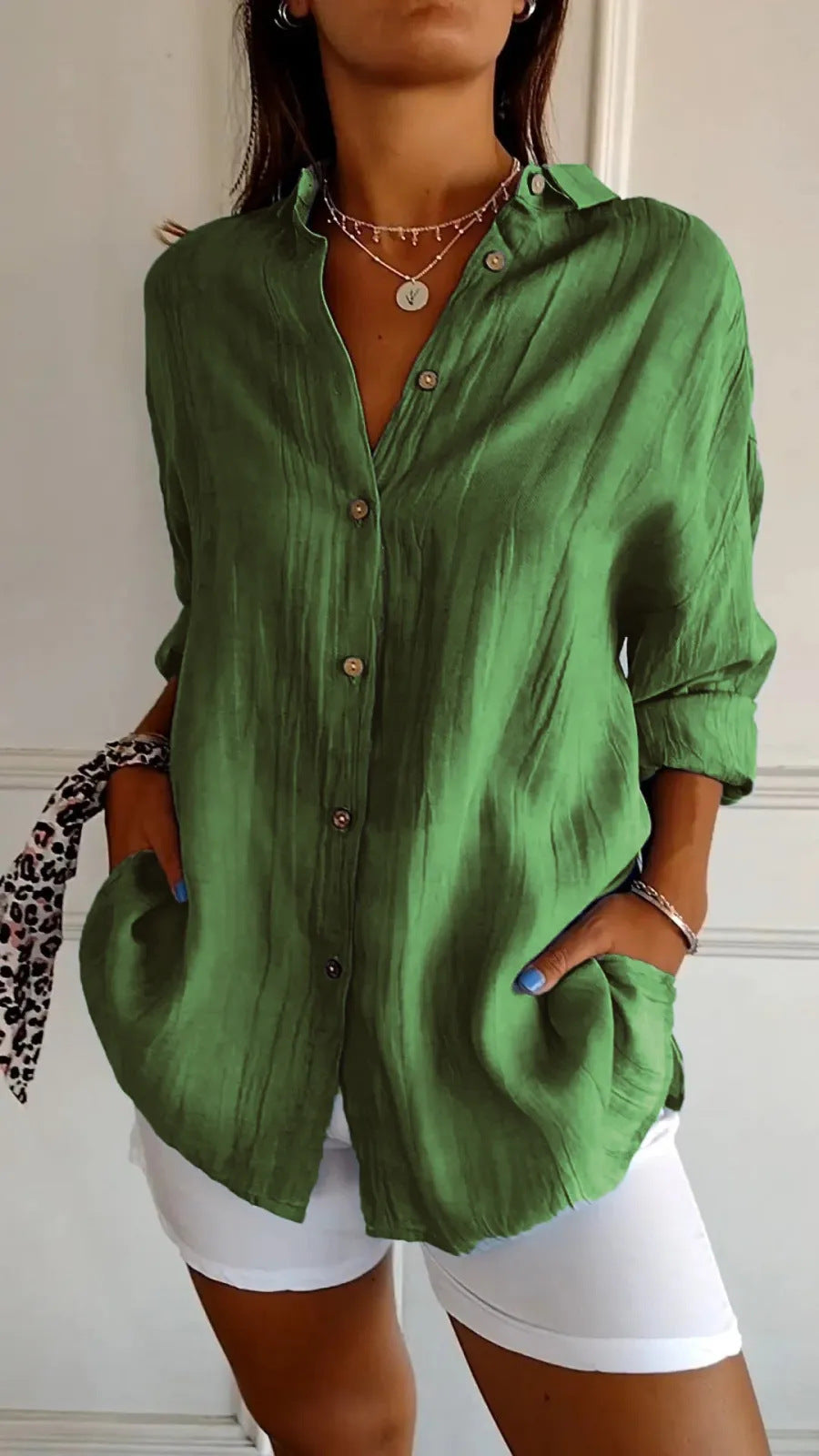 Person wearing a green button-up shirt and white shorts against a neutral background