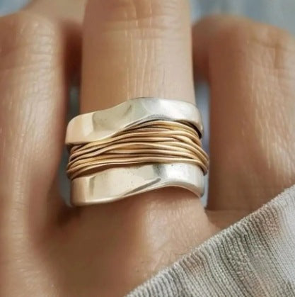 Gold and silver ring on a finger with a blurred background