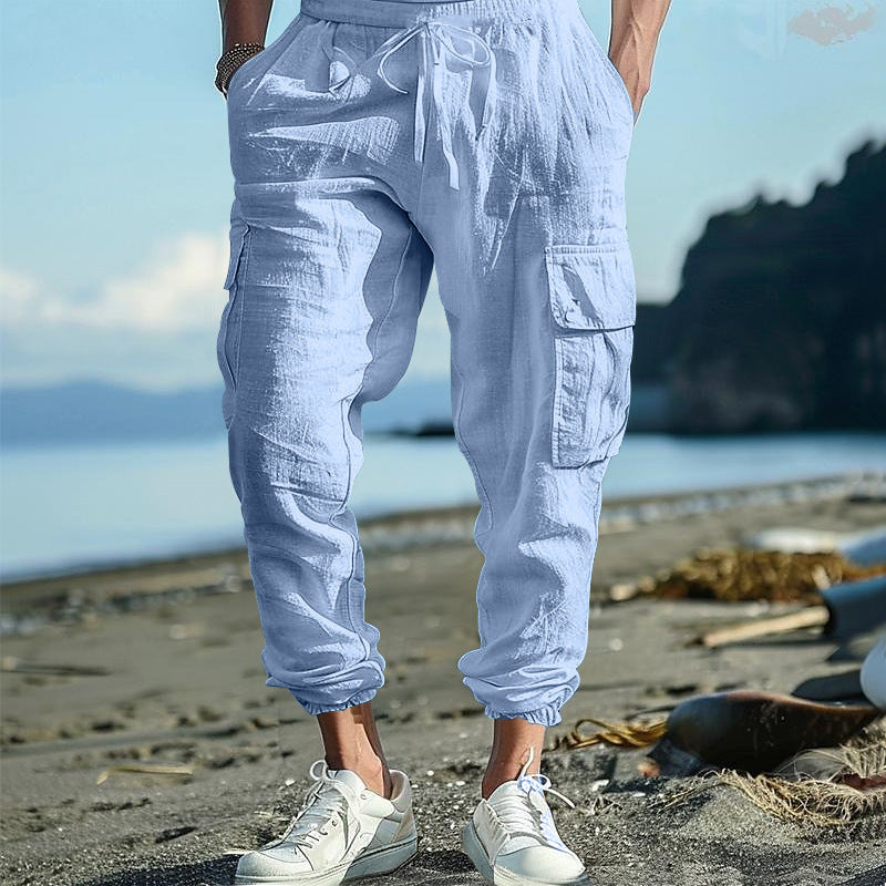 Person wearing light blue cargo pants and white sneakers on a beach.