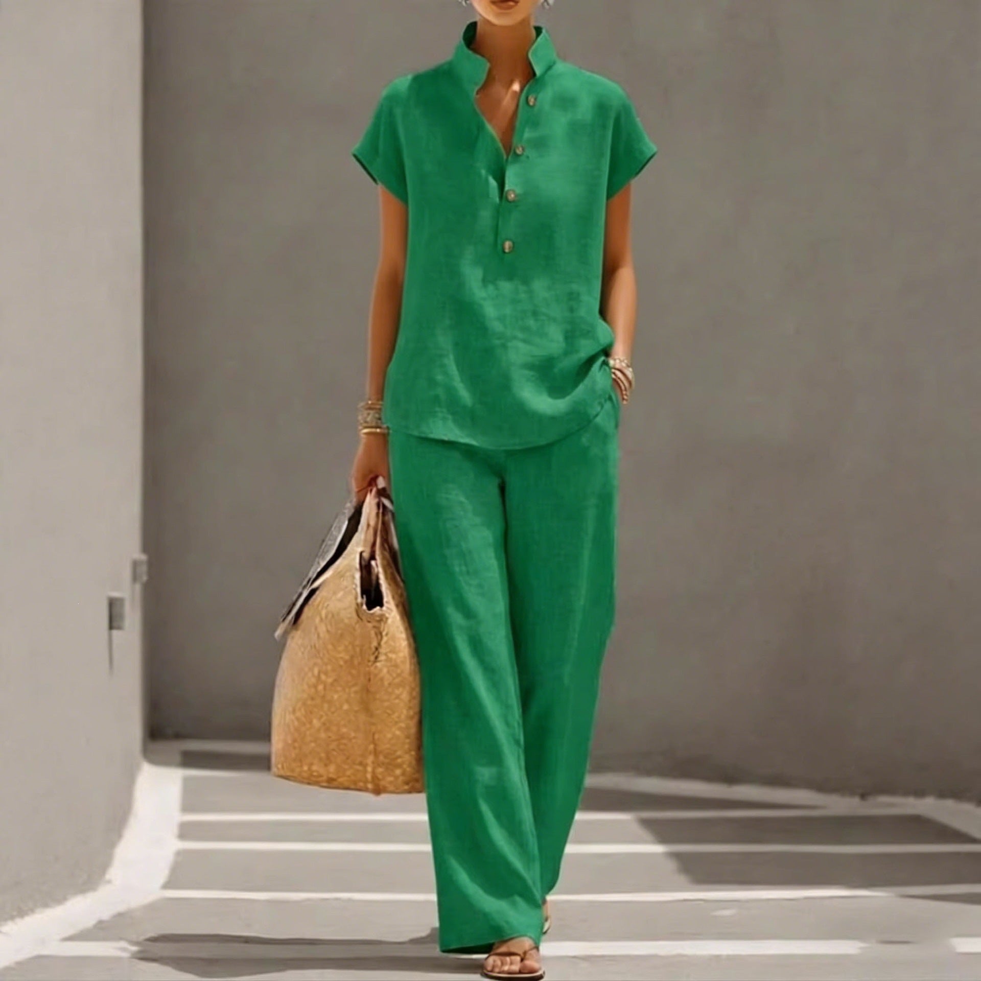 Person wearing a green outfit holding a straw bag against a gray wall.