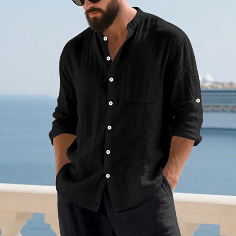Man wearing a black button-up shirt with a blurred coastal background