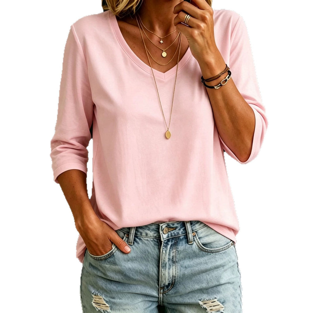 A woman wearing a light pink long-sleeve V-neck top and light blue distressed jeans, shown from the shoulders down against a plain white background.