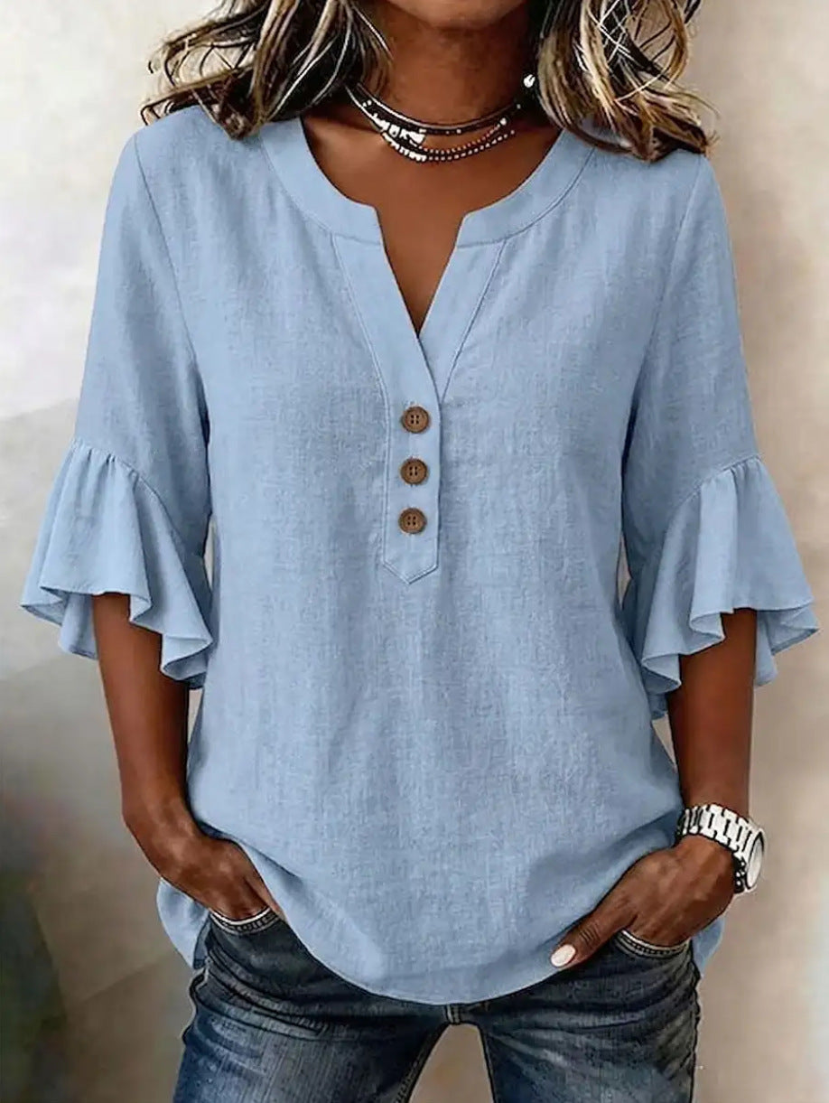 Woman wearing a light blue blouse with ruffled sleeves against a neutral background