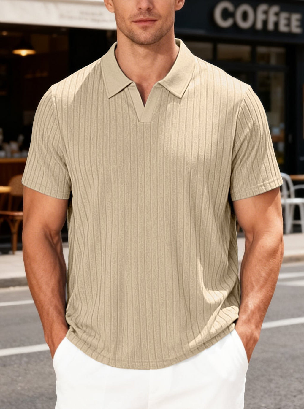 Man wearing a beige short-sleeve shirt standing outdoors with a coffee shop in the background.