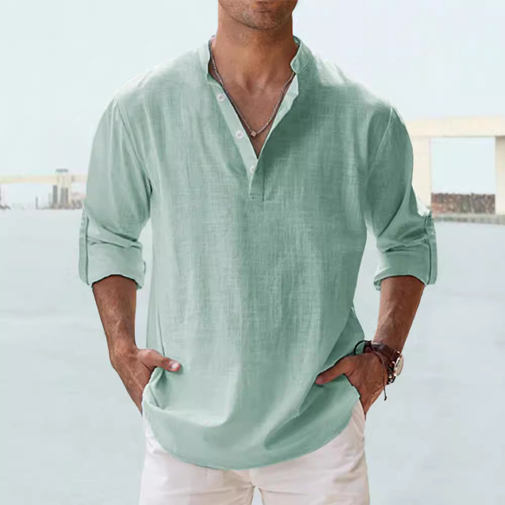 Man wearing a light green shirt with rolled-up sleeves against a blurred background