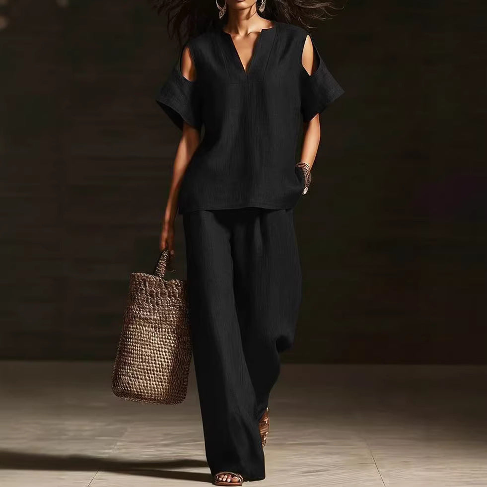 Woman in a black outfit holding a woven bag against a dark background