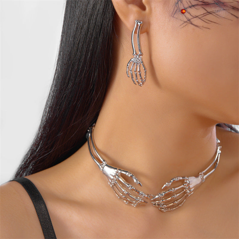 Silver skeleton hand necklace and earrings on a mannequin with a plain background