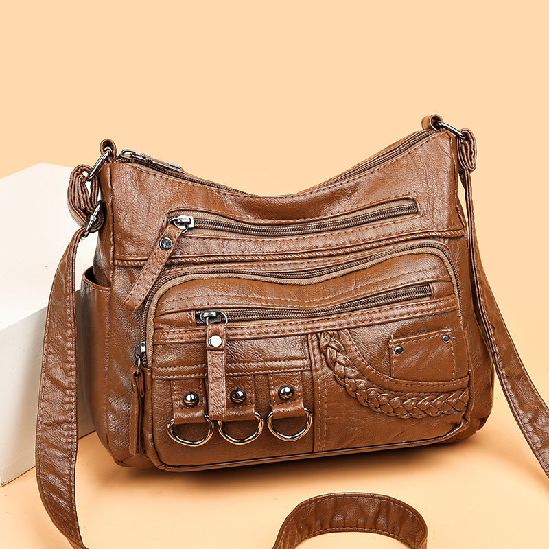 Brown leather handbag with multiple pockets and straps on a beige background