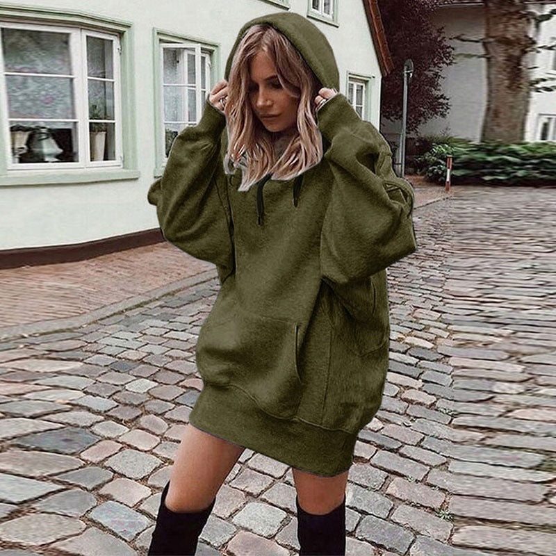 Person wearing a green hoodie dress on a cobblestone street.