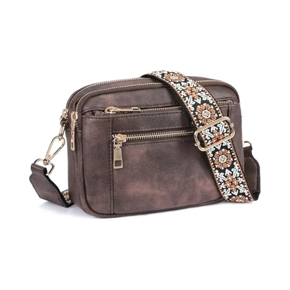 Brown leather crossbody bag with an embellished strap on a white background