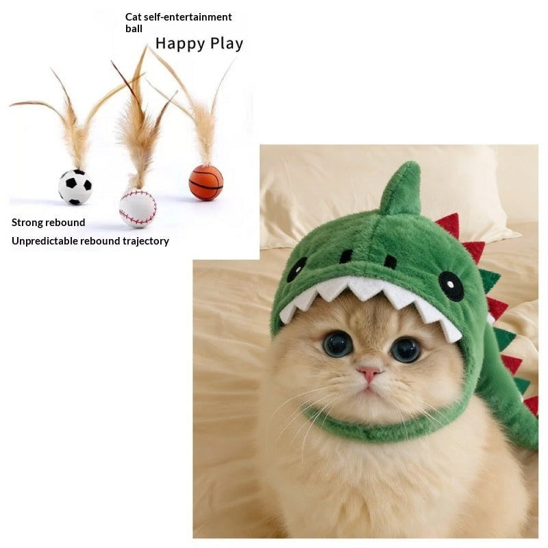 A fluffy cream-colored cat wearing a green dinosaur-shaped plush hood with white teeth and red spikes, shown on a bed. A smaller inset at the top left shows feather self-entertainment balls labeled 'Happy Play' with text 'Strong rebound' and 'Unpredictable rebound trajectory'.