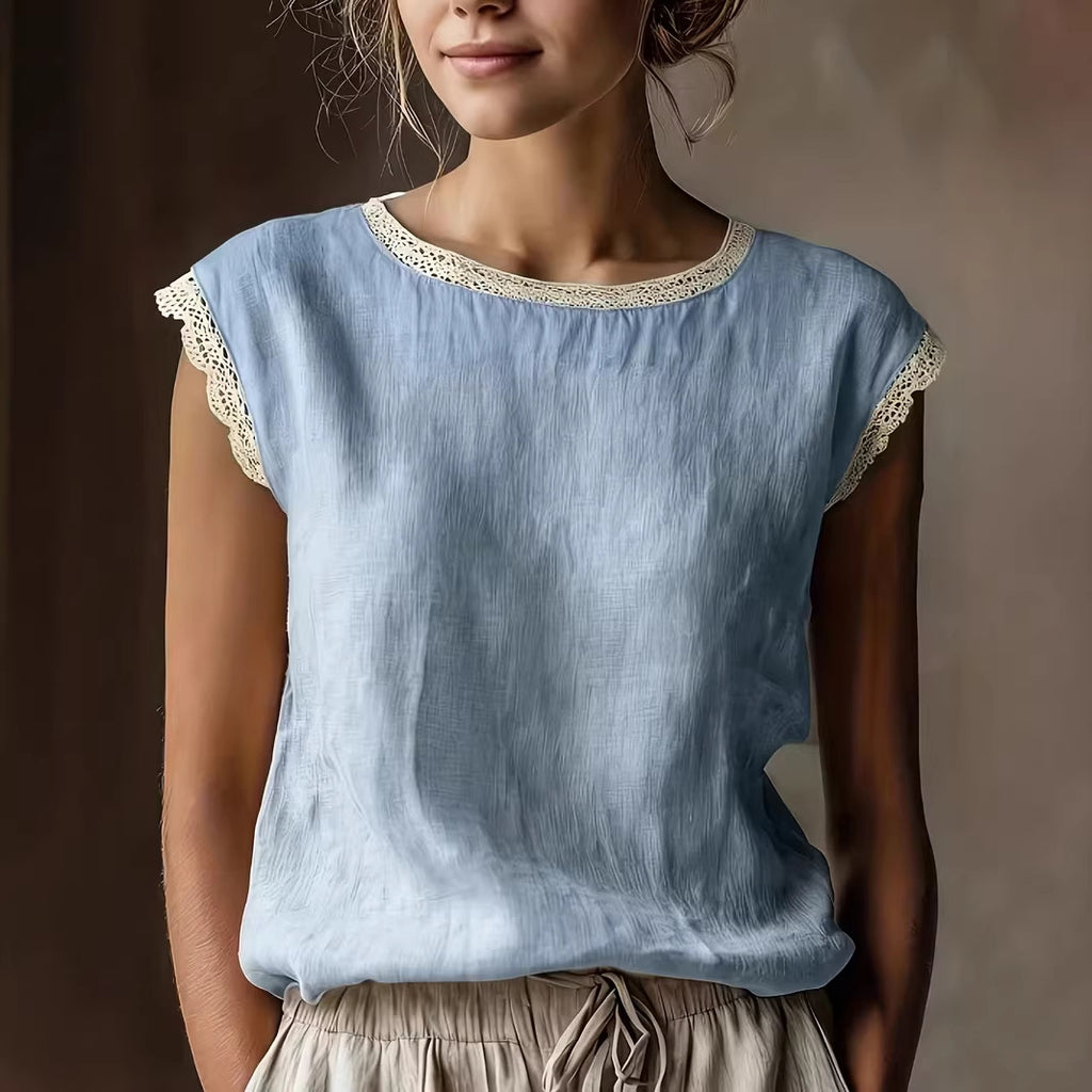 Woman wearing a light blue top with lace trim against a neutral background
