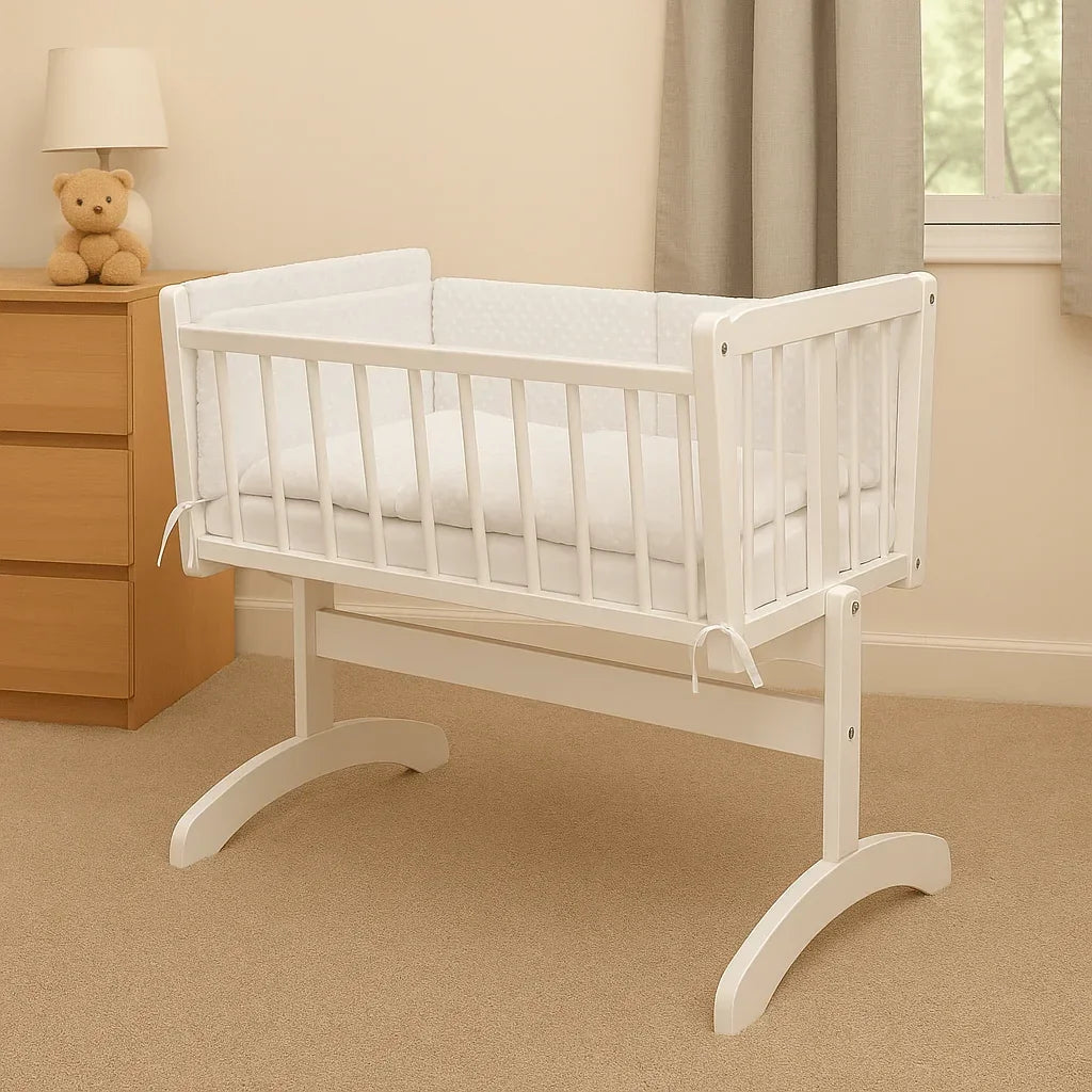 White wooden cradle with white dimple quilt and bumper bedding set in a cozy nursery.