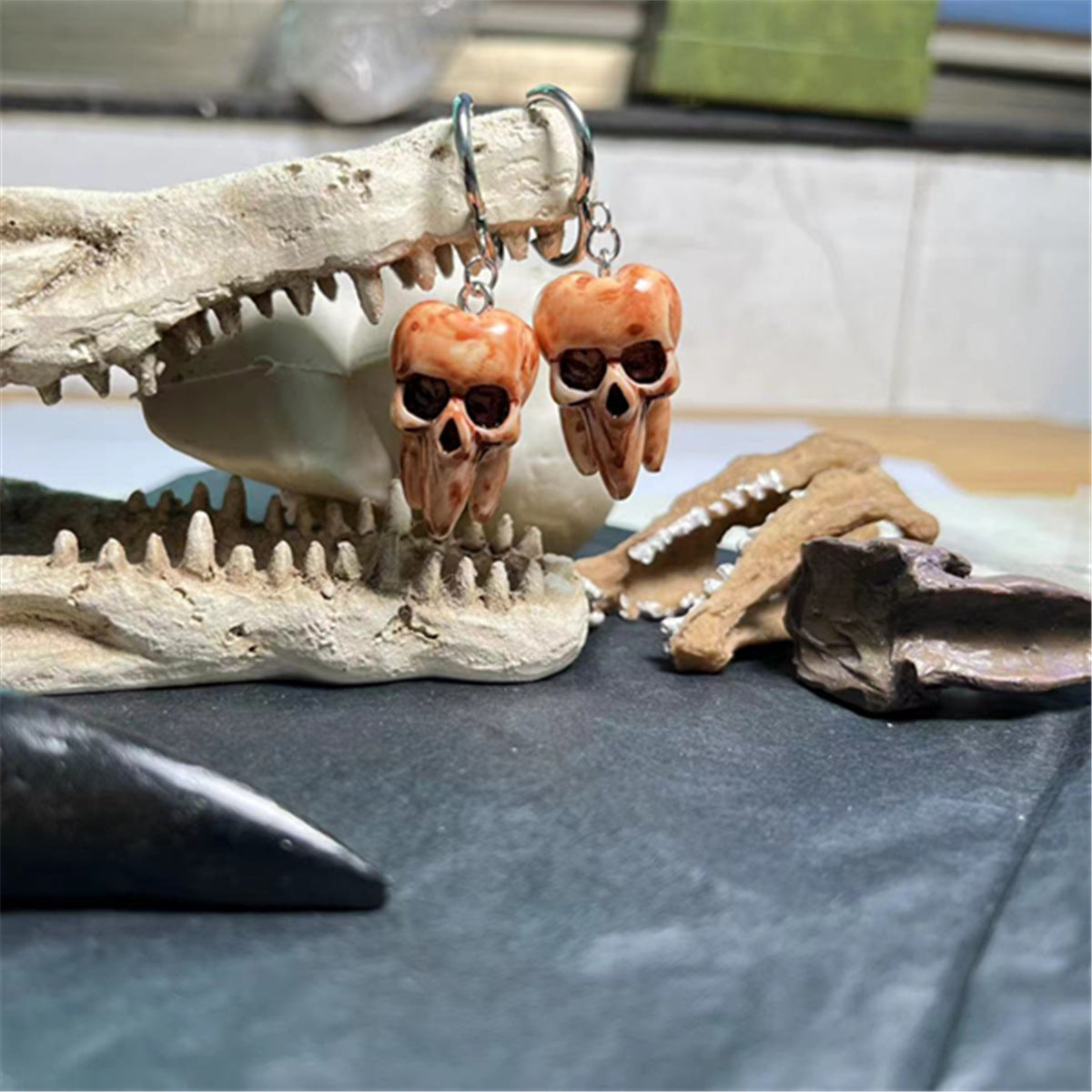 Skull-shaped earrings hanging from a bone structure on a table.