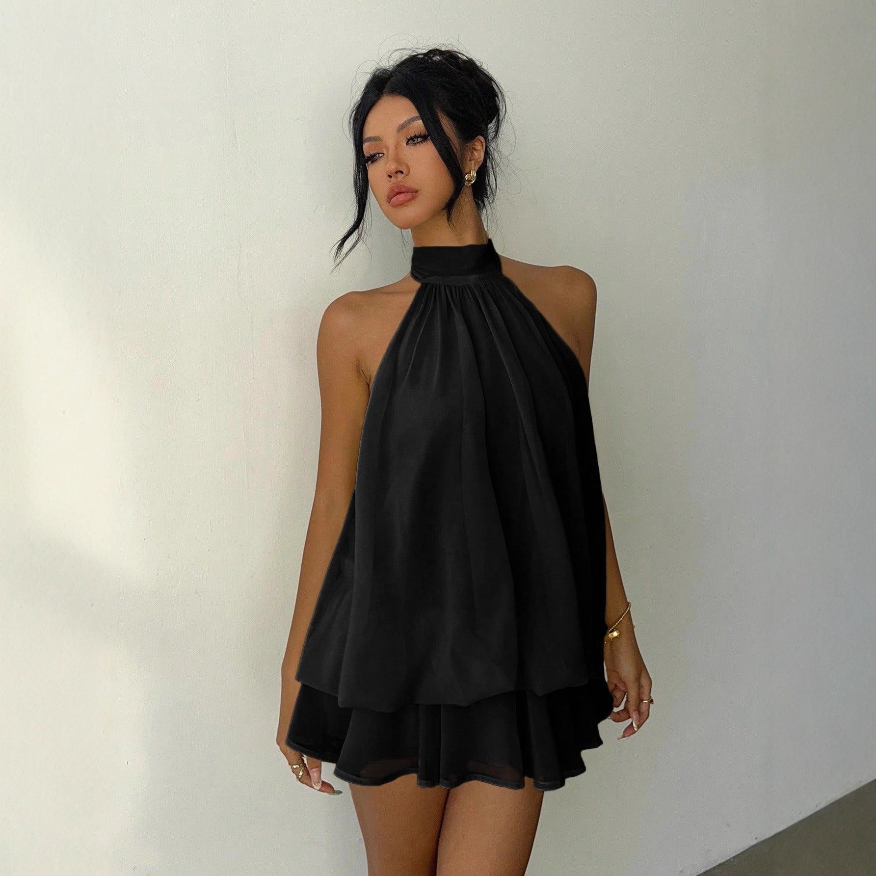 Woman wearing a black halter neck dress against a plain background