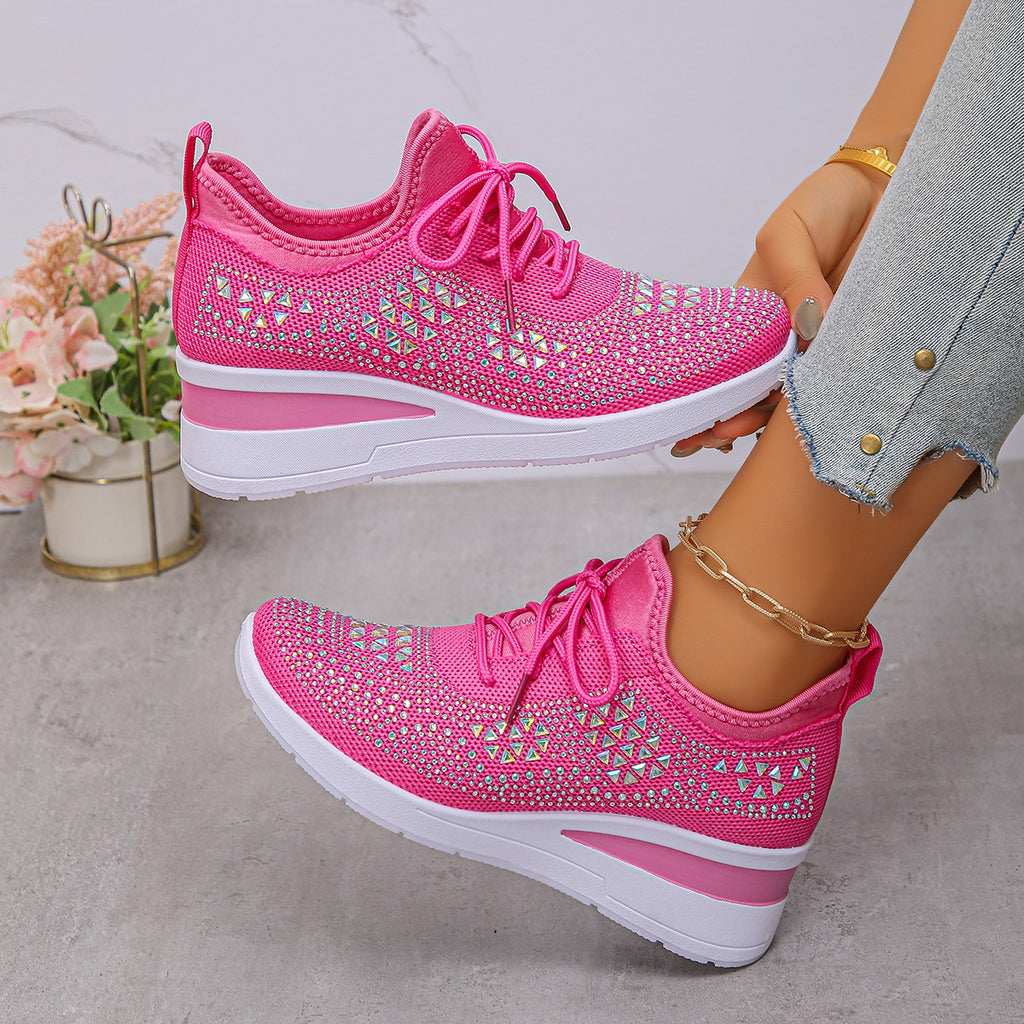 Pink sneakers with rhinestone details worn by a person on a light gray surface.