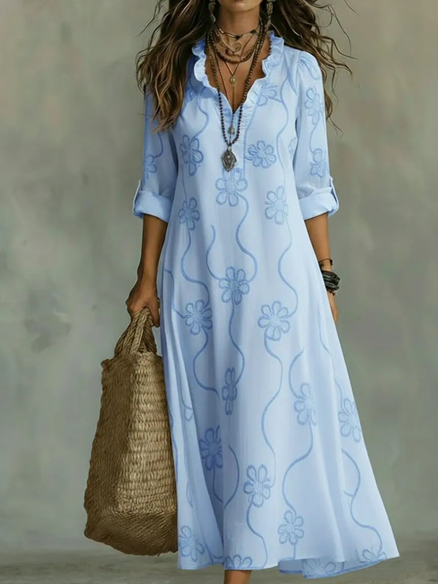 Woman wearing a light blue floral dress holding a woven bag against a neutral background