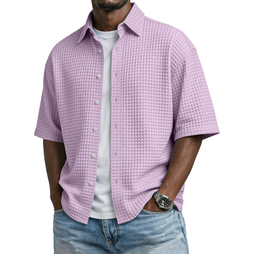 Man wearing a light purple checkered shirt over a white t-shirt with blue jeans on a white background
