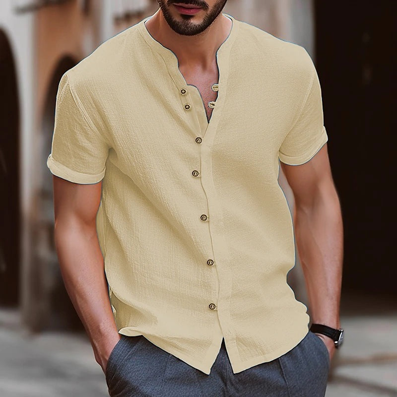 Man wearing a beige short-sleeve button-up shirt with a blurred background