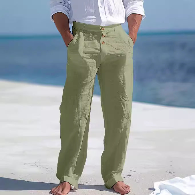Person wearing green pants and a white shirt on a beach.
