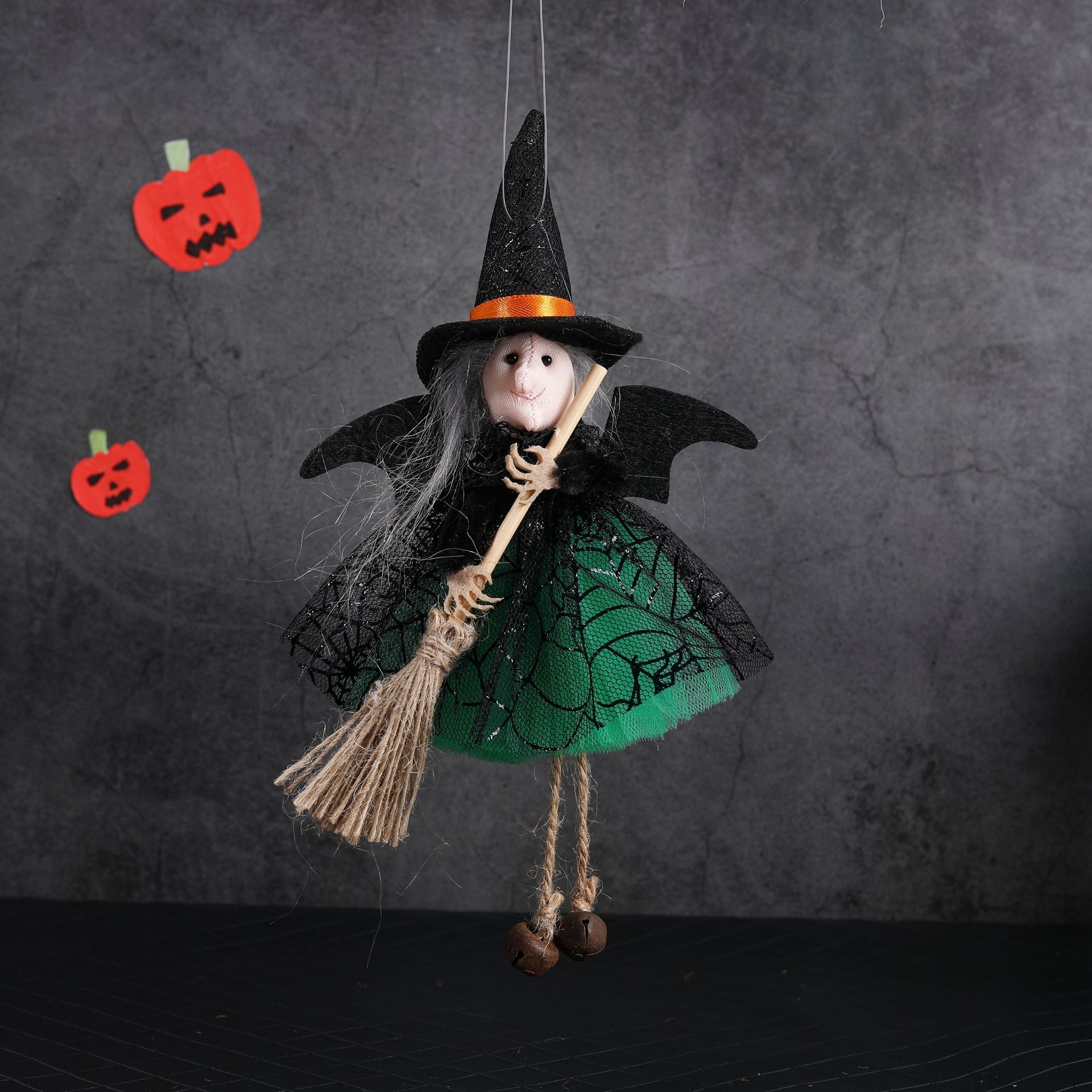 Halloween-themed decoration with a witch figurine, broom, and pumpkins on a dark background