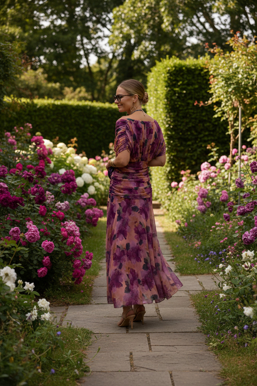 Woman wearing a floral dress background of flowers and pavement.