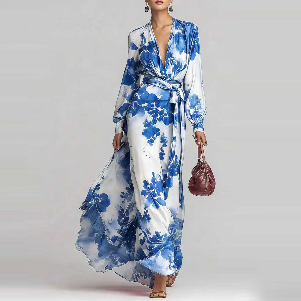 Woman wearing a blue and white floral dress holding a red handbag on a plain background