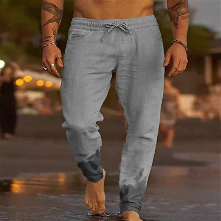 Person wearing light gray jogger pants walking on a wet surface with a blurred background