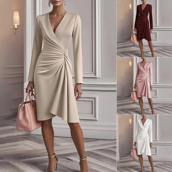 Woman in a beige wrap dress holding a pink handbag in an elegant interior setting.