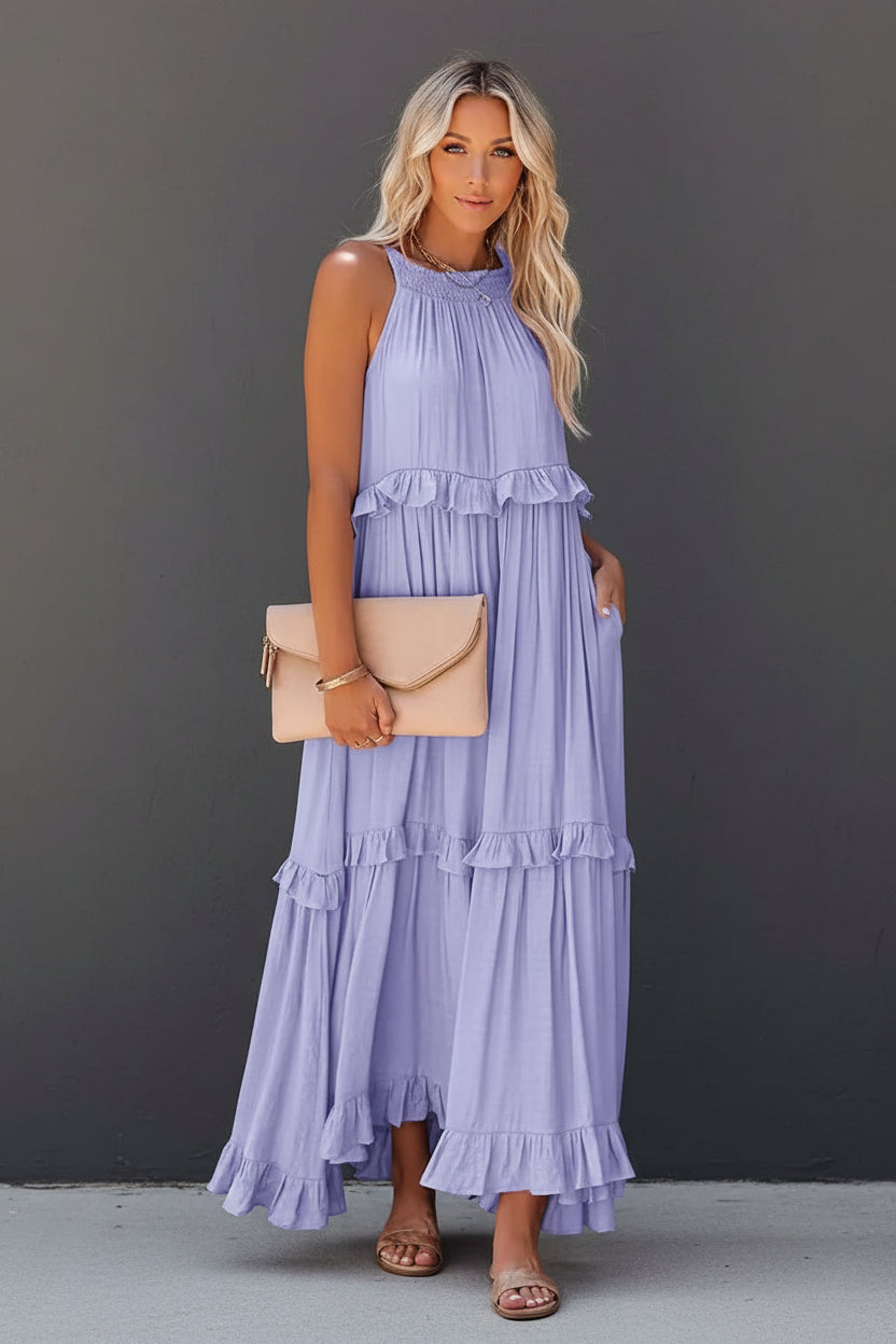 Woman wearing a light purple ruffled dress holding a beige clutch against a white background