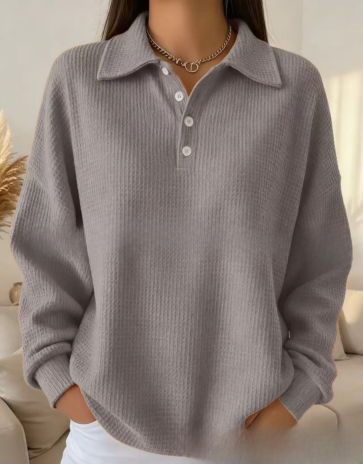Person wearing a gray ribbed sweater with a blurred background