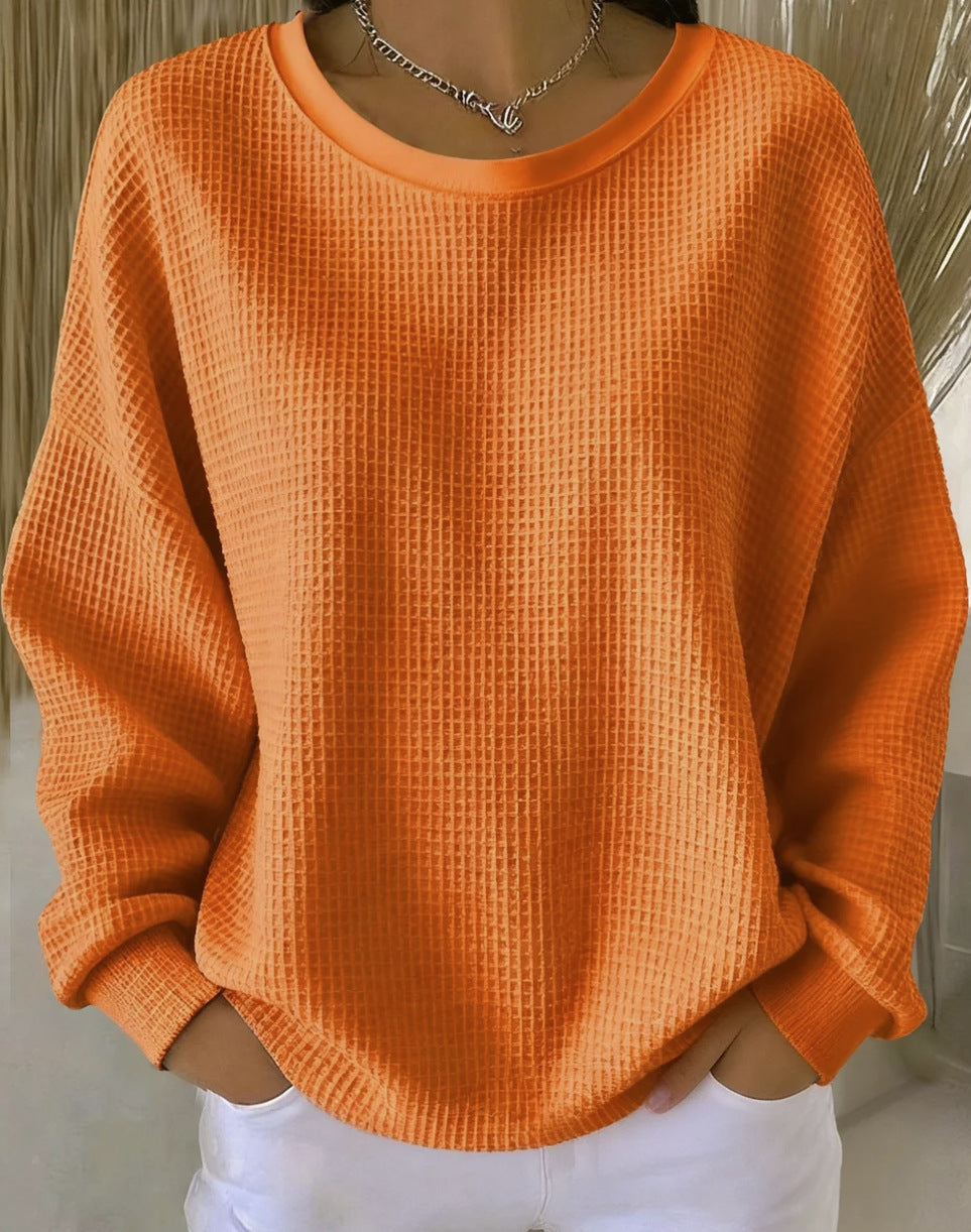 Orange textured sweater worn by a person against a neutral background